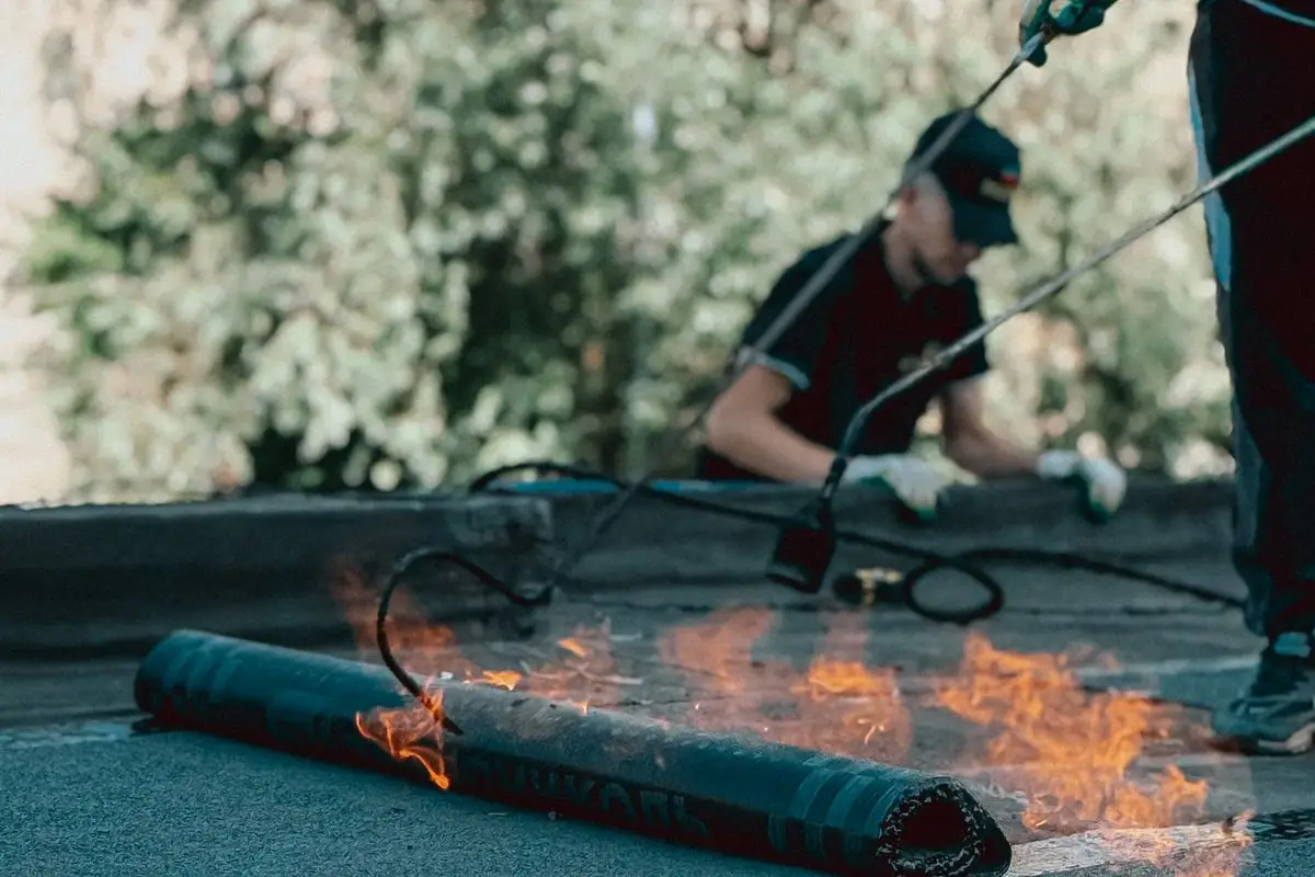 Roofer installing torch-down membrane on a flat roof