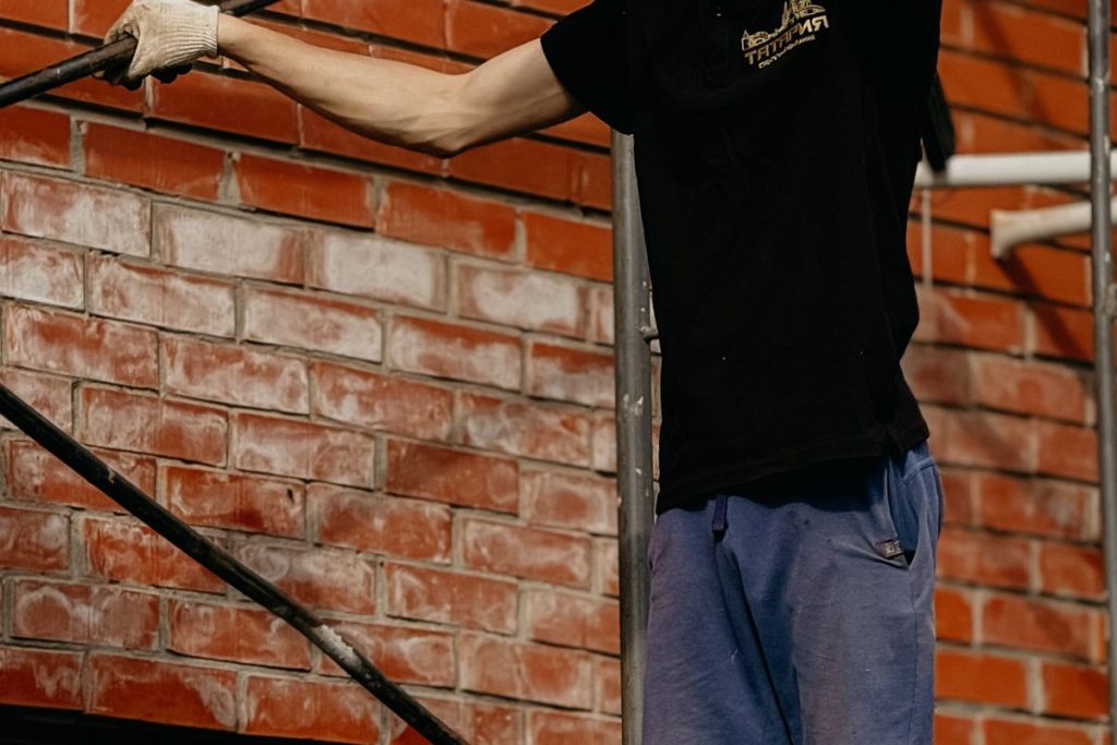 Mason repairing a brick wall on scaffolding