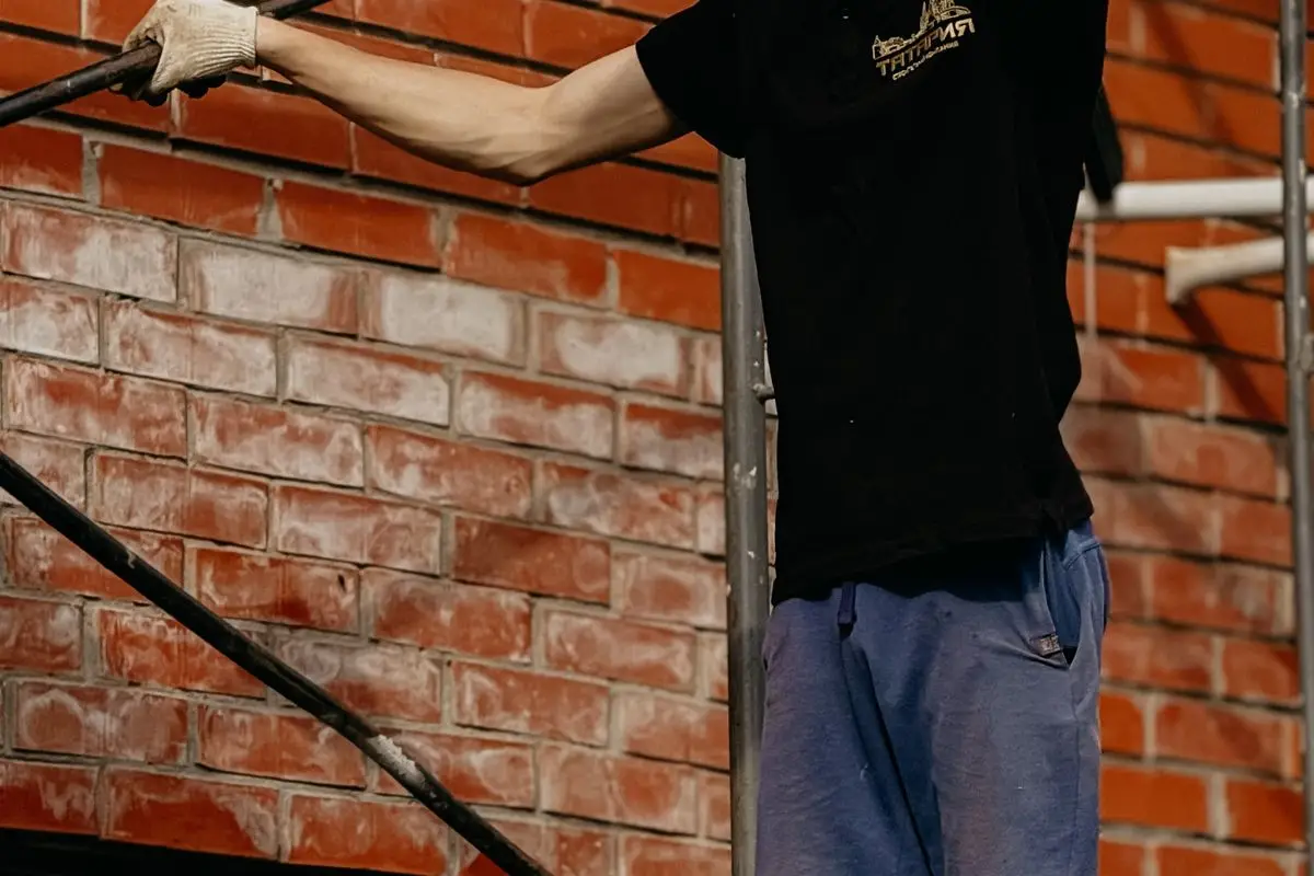 Mason repairing a brick wall on scaffolding